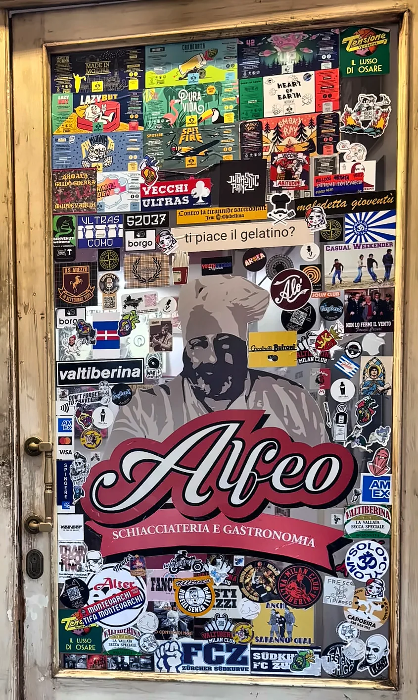La porta d'ingresso di Alfeo coperta di adesivi, con il logo dello chef al centro