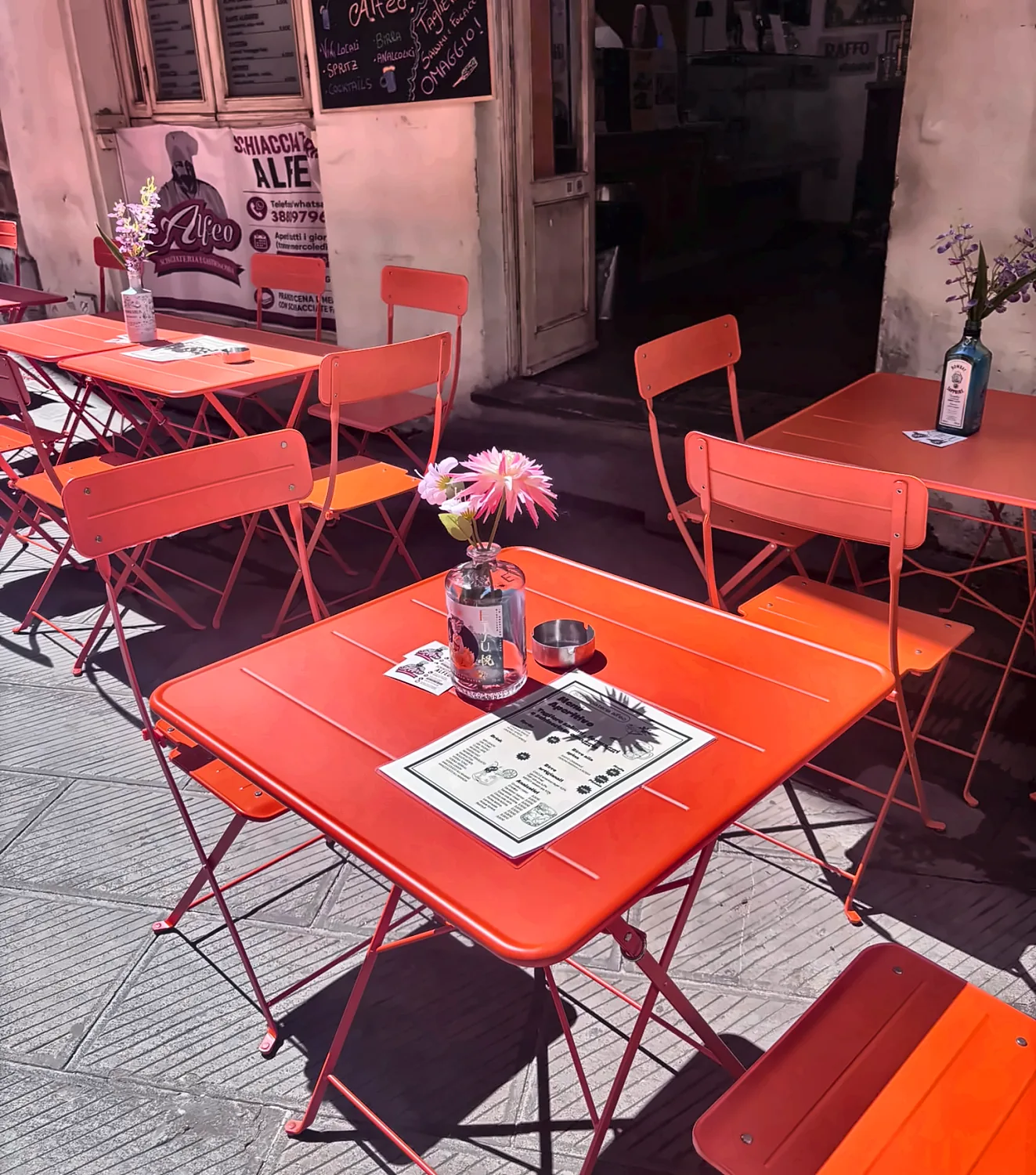 Tavolino arancione con fiori e menu aperitivo